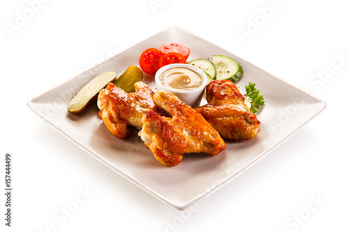 Grilled chicken wings with vegetables on white background