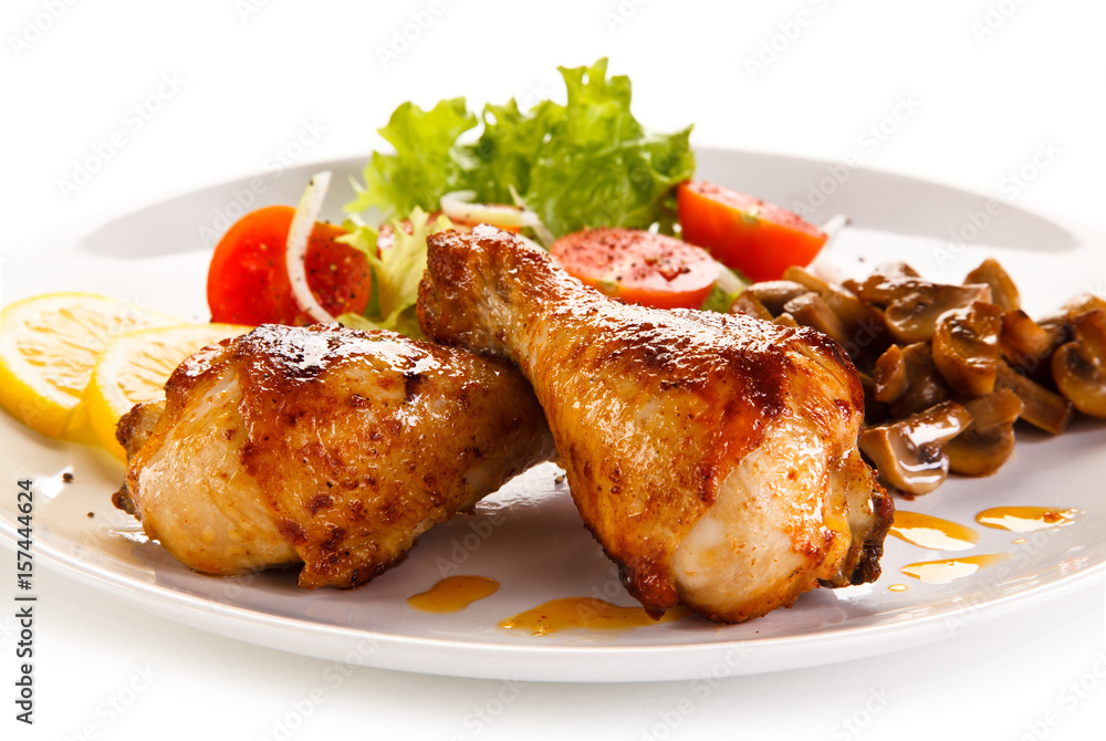 Grilled chicken drumsticks with vegetables on white background Grilled chicken drumsticks with vegetables on white background