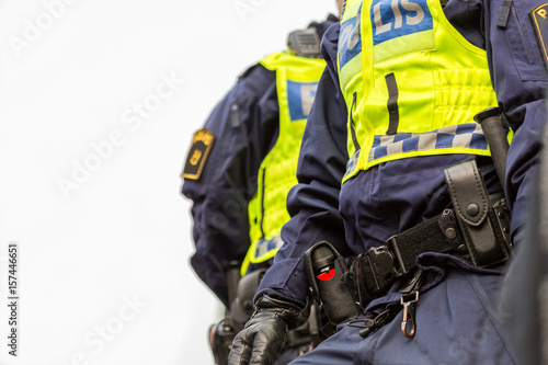 Two police officers, close up of upper body with vest and equipment belt.