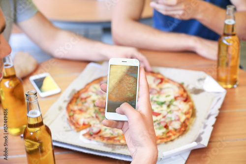 Man taking photo of pizza with smart phone