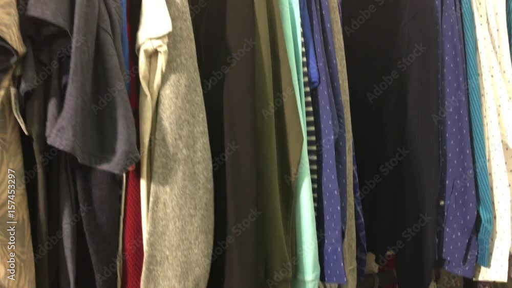 Bright colored clothing is panned while on racks under artificial lighting. Bright colored clothing is panned while on racks under artificial lighting.