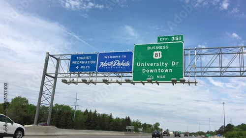 Blue welcome to North Dakota sign above highway on partly cloudy day.  