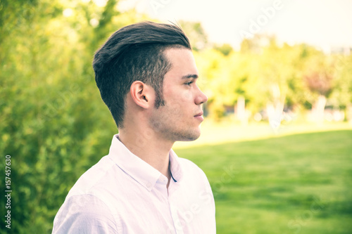 Attractive young man in city park, looking away, profile shot