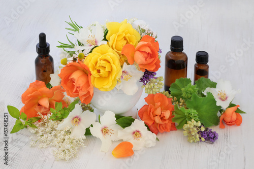 Flower and herb selection with aromatherapy essential oil bottles and mortar with pestle.