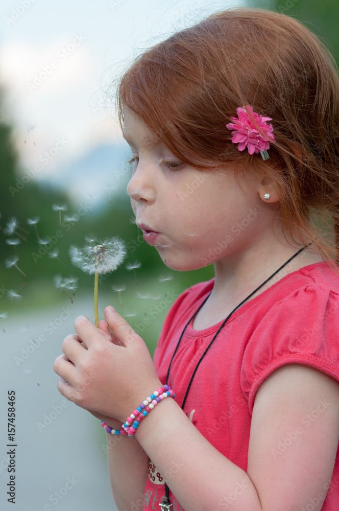 Red hair child blows on a flower Red hair child blows on a flower