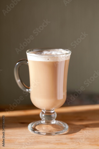 Glass cup with cappuccino on the table. Smooth focus. Cinnamon.