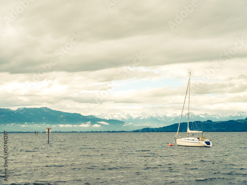Sailing Boat on lake Constance with dramatic sky and Swiss Alps in Background