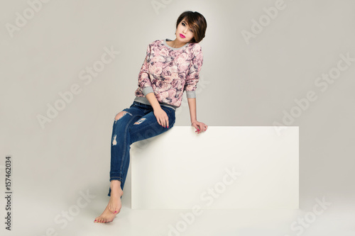 Charming women in jacket with flowers and blue jeans with holes.