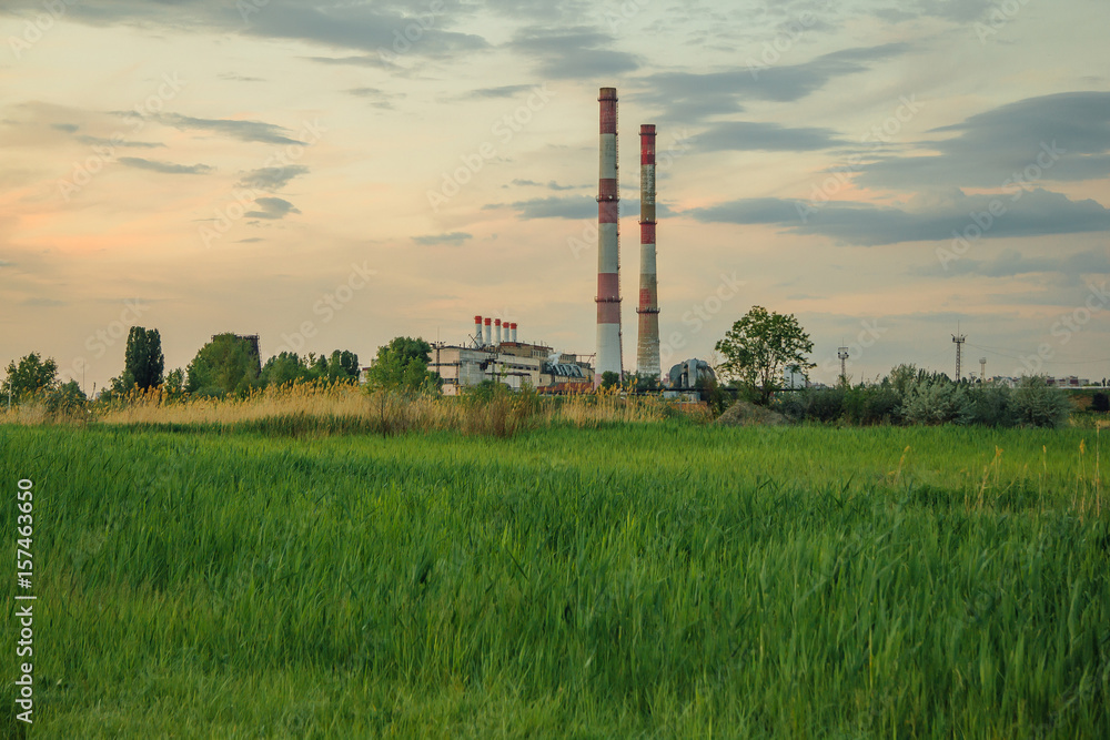Green meadow on background of industrial area 
