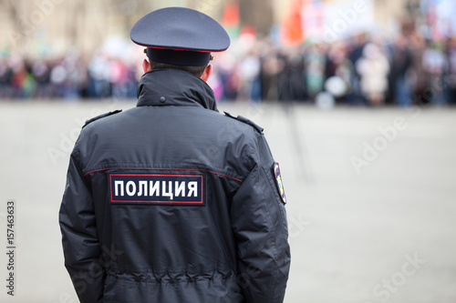 Russian policeman officer stands to opposite crowd with inscription Police on the uniform jacket, Russia, copy space