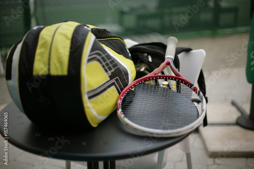 Tennis racket and bag on black table - sport and object concept; selective focus.