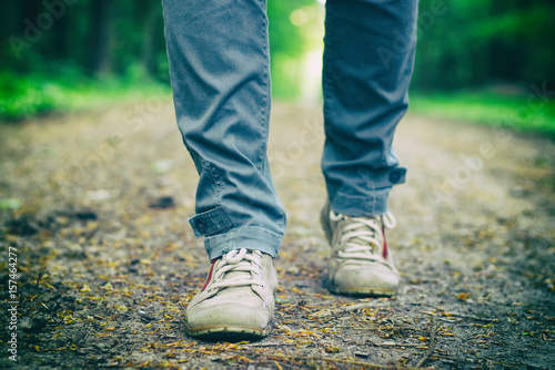 A tourist woman with hiking shoes walk on a forest path. Women's hiking boots. 