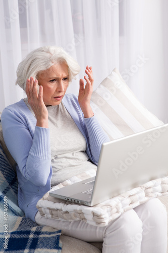 Laptop computer broke in elderly woman. Frustrated lady looking disappointed by new computer technologies.