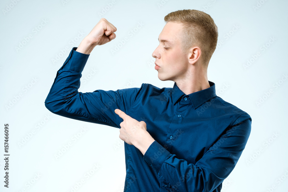 Young handsome guy pointing at his biceps Young handsome guy pointing at his biceps