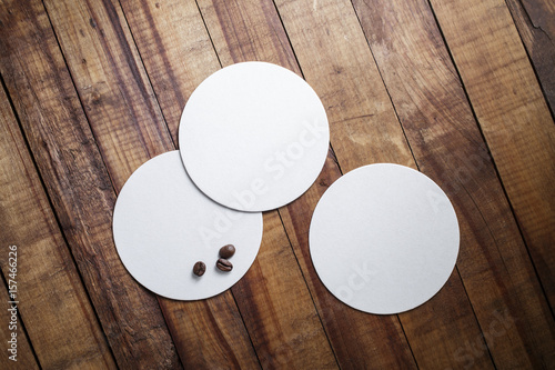 Blank square beer coasters and coffee beans on vintage wood table background. Top view.