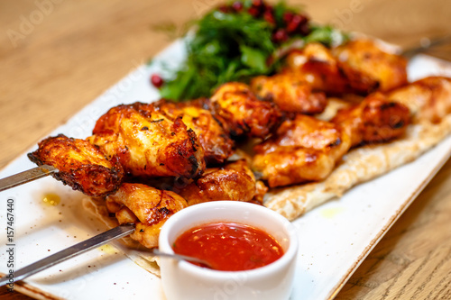 Chicken kebab with tomato sauce, herbs and pomegranate seeds.
