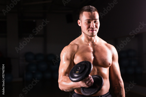 Portrait of strong healthy handsome Athletic Man Fitness Model posing with a dumbbell.