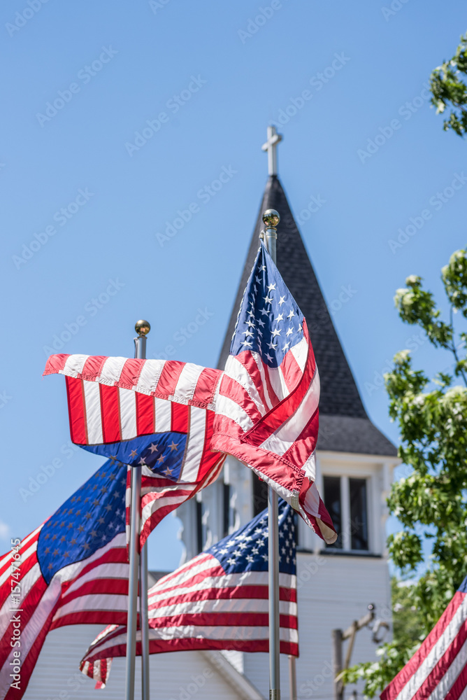 US flags twisting and waving in wind outside old church steeple in Illinois