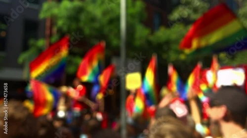 Rainbow flags flying on a float and in the hands of spectators on the sidelines of a summer gay pride parade in Greenwich Village, New York City photo