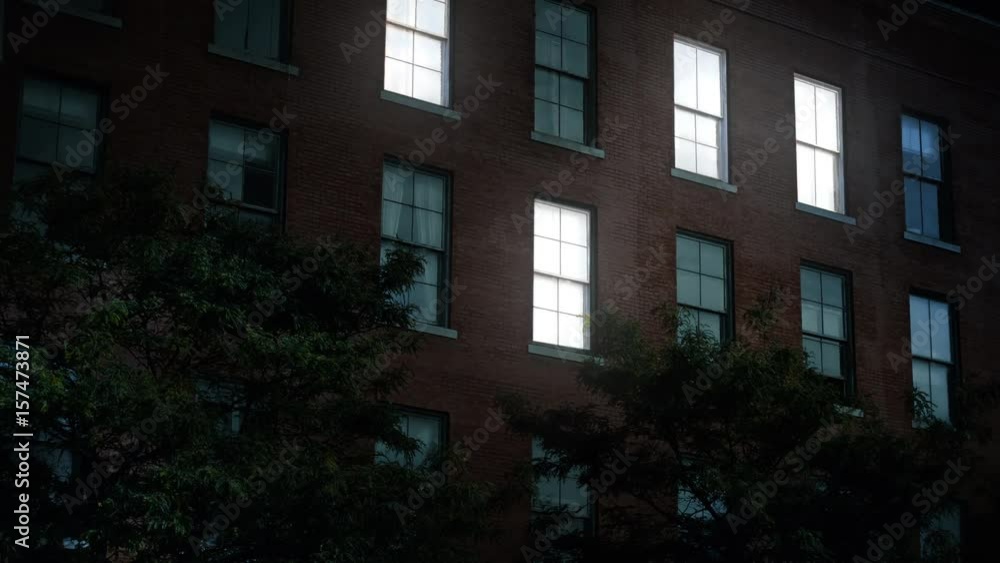 A typical New York style apartment or office building establishing shot at night with the lights from a window turning on and off. Simulated