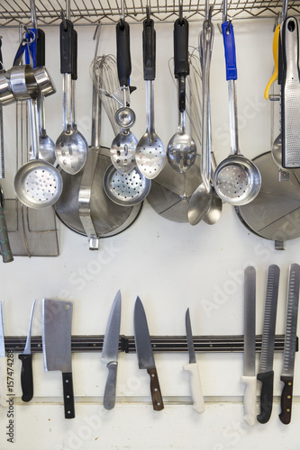 Assorted knives and cooking utensils on a wall in a restaurant kitchen