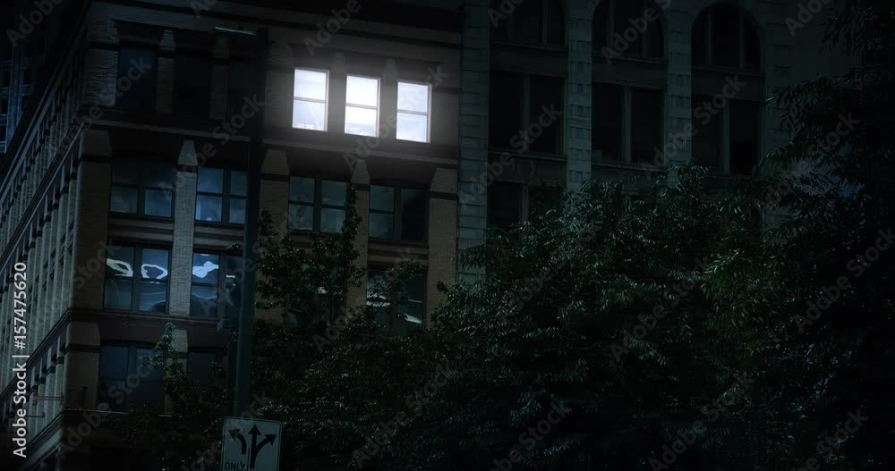 A typical New York style apartment or office building establishing shot at night with the lights from a window turning on and off. Simulated