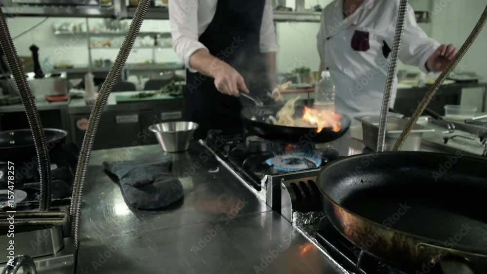 Chef is making flambe sauce on restaurant kitchen with onion and wine Chef is making flambe sauce on restaurant kitchen with onion and wine