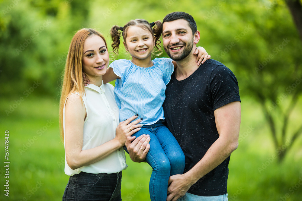 Obraz premium Happy young mother, father and daughter in summer park