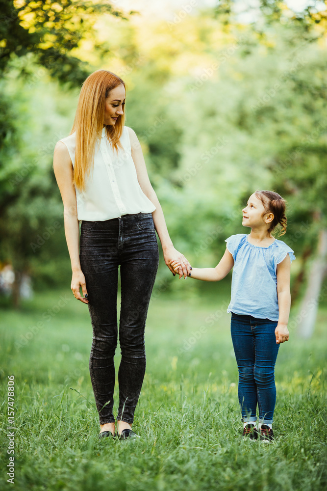 Mother and daughter having fun in the park. Happy family concept. Beauty nature scene with family outdoor lifestyle. Happy family resting together. Happiness and harmony in family life.