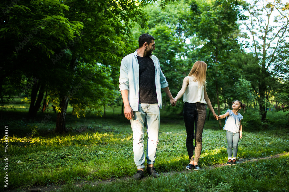 Fototapeta premium happy mother, father and little girl walking in summer park and having fun