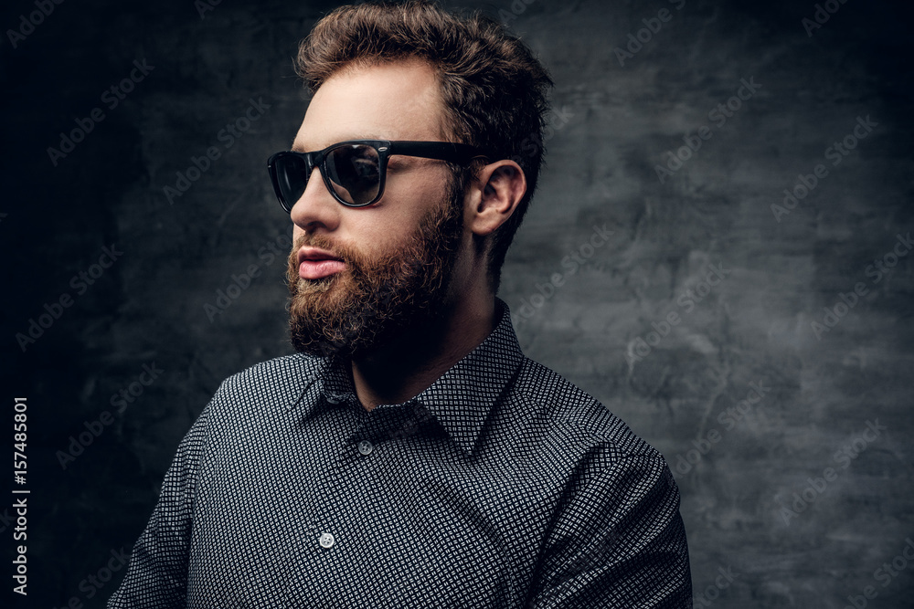 Obraz premium Stylish bearded male in sunglasses over grey background.