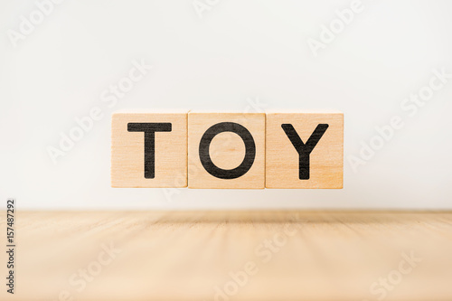 Surreal abstract geometric floating wooden cube with vocabulary "TOY" concept on wood floor and white background