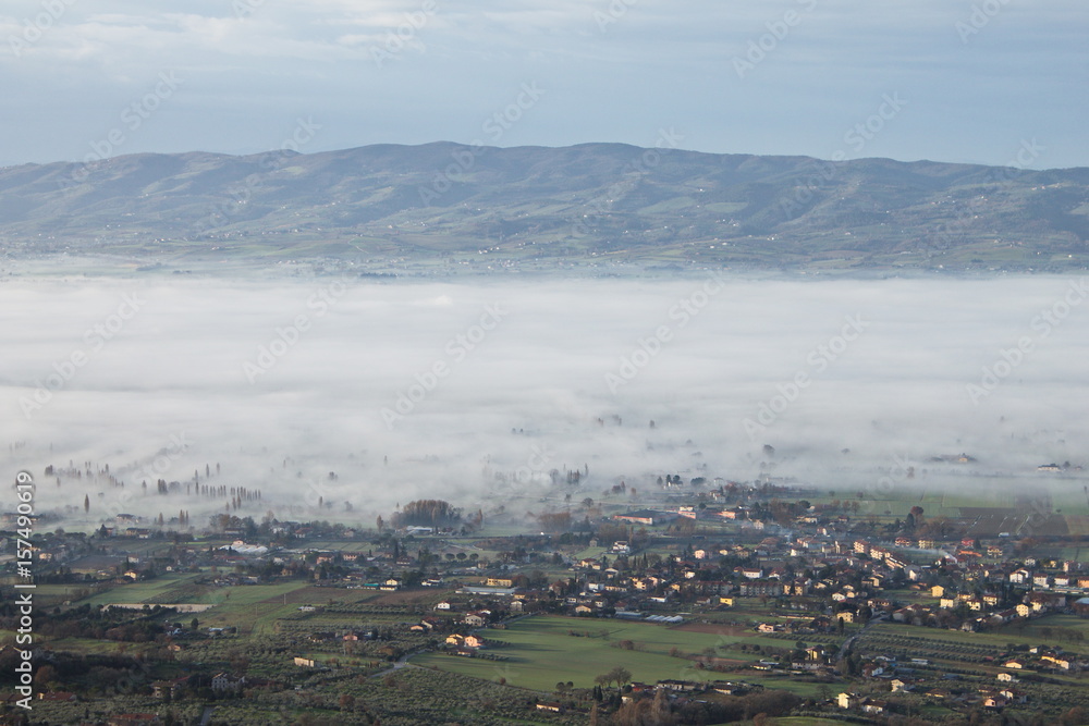 An aerial view of a valley half filled by fog
