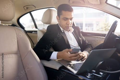 Serious businessman in a car with laptop
