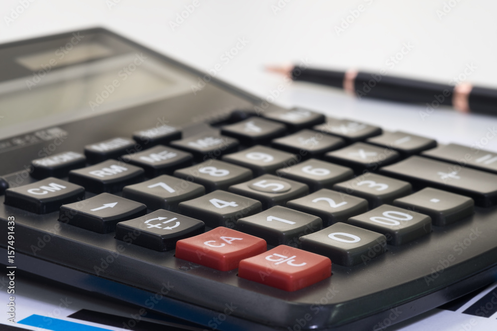 close up numeric keypad on black calculator with blurred pen for financial; accounting; analyst concept. close up numeric keypad on black calculator with blurred pen for financial; accounting; analyst concept.