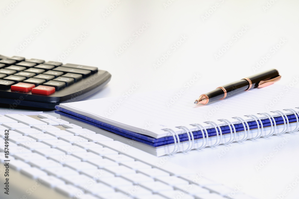 ball pen on notebook with blurred calculator and keyboard. ball pen on notebook with blurred calculator and keyboard.