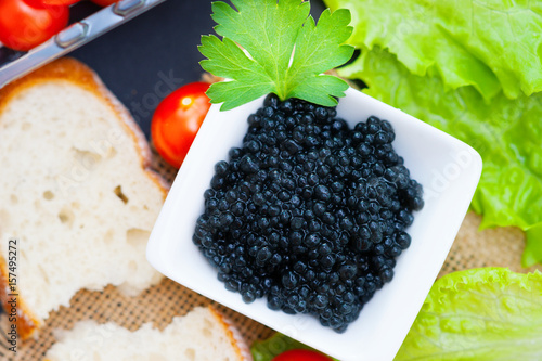 Dish with a black caviar, tomatoes and a piece of white bread 