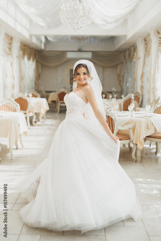 Beautiful bride posing in wedding dress in fashion hotel