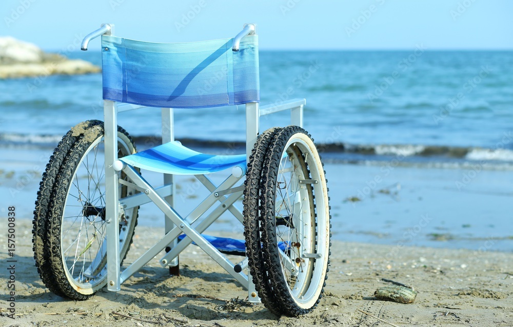 Fototapeta premium wheelchair by the sea in summer with large wheels