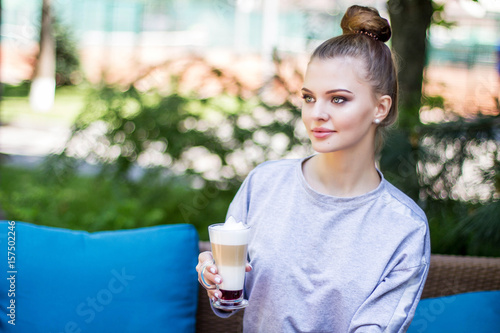 Young woman drinks coffee in a cafe uotdoors photo