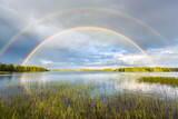 Rainbow in midsummer over the lake in beautiful landscape in Finland