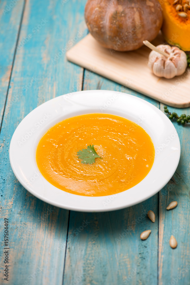 Top view of pumpkin and carrot soup with cream and parsley on blue wooden background. Top view of pumpkin and carrot soup with cream and parsley on blue wooden background.