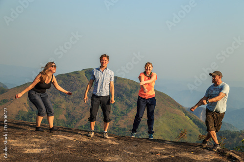 Group of tourists jumping on top of the mountain.