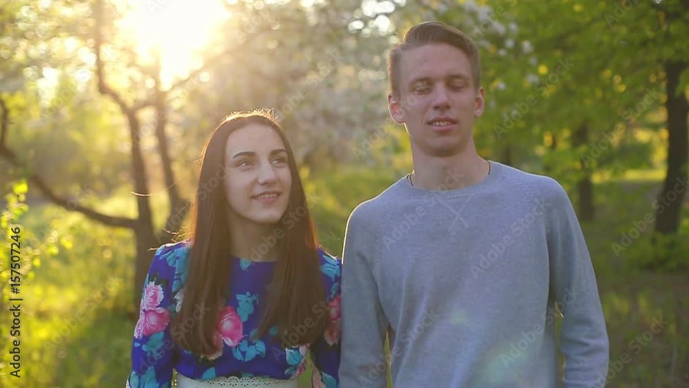 Loving guy and girl in a blooming apple orchard at sunset Loving guy and girl in a blooming apple orchard at sunset