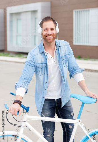 Casual guy with his bike in the street listening music photo