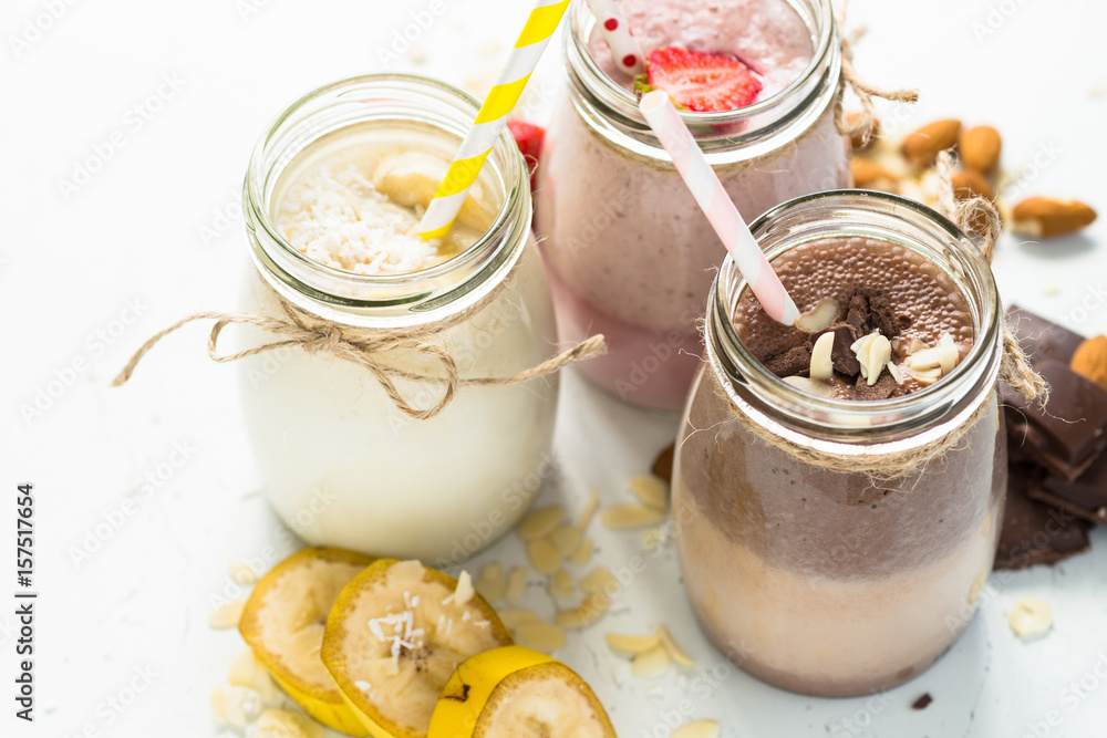 Banana chocolate and strawberry milkshakes in jars on white. Banana chocolate and strawberry milkshakes in jars on white.