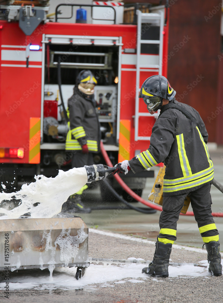 Obraz premium Firefighter training and fire extinguishing with foam and truck