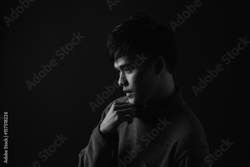 Young asian man's portrait against black background © makistock