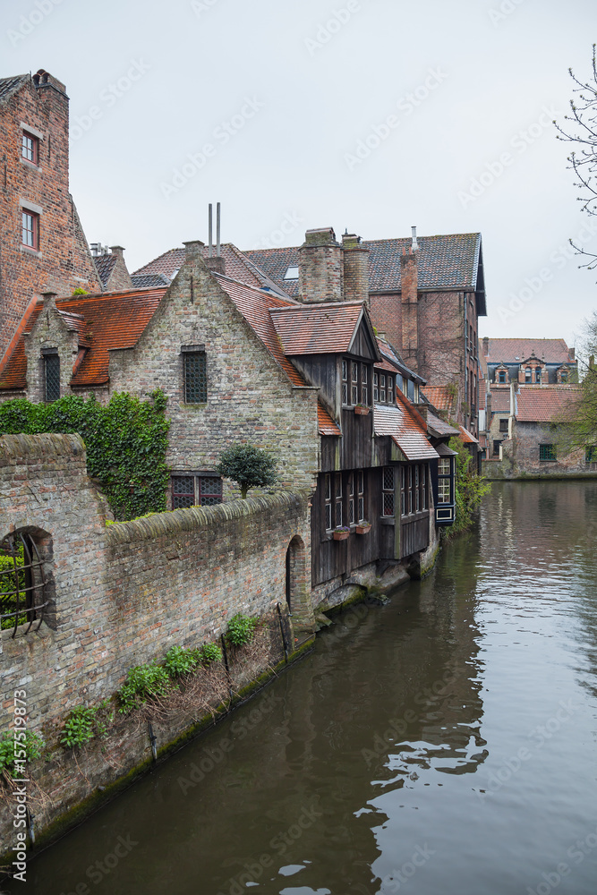 Fototapeta premium View on canal with old picturesque houses with brick and wooden facades in historic part of Bruges (Brugge), Belgium