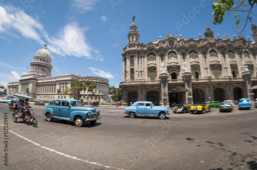 Bright wide-angle view of the daily life on one of the main streets in central Havana, Cuba with classic taxi cars passing the Capitolio and Gran Teatro de La Habana landmarks © lazyllama